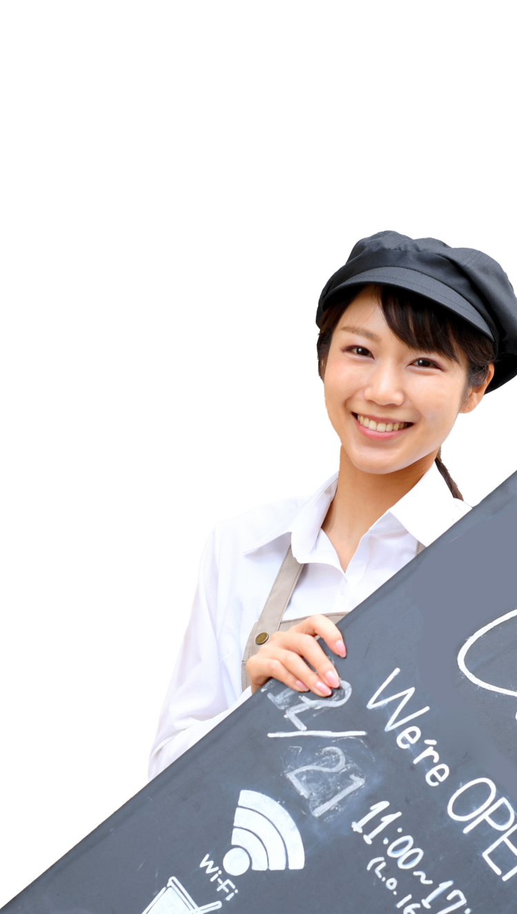 写真：黒いキャップをかぶったカフェの店員が「Cafe」と書かれた看板を持って微笑んでいる。